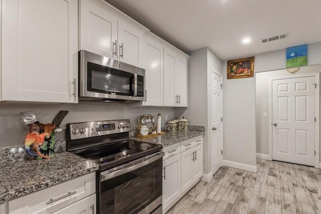 kitchen featuring stone countertops, white cabinets, light wood-type flooring, and stainless steel appliances