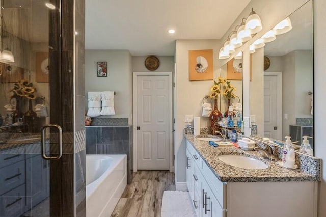 bathroom featuring a tub, dual vanity, and hardwood / wood-style floors