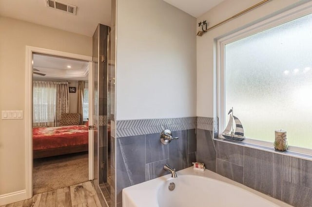 bathroom featuring a tray ceiling, wood-type flooring, and a tub