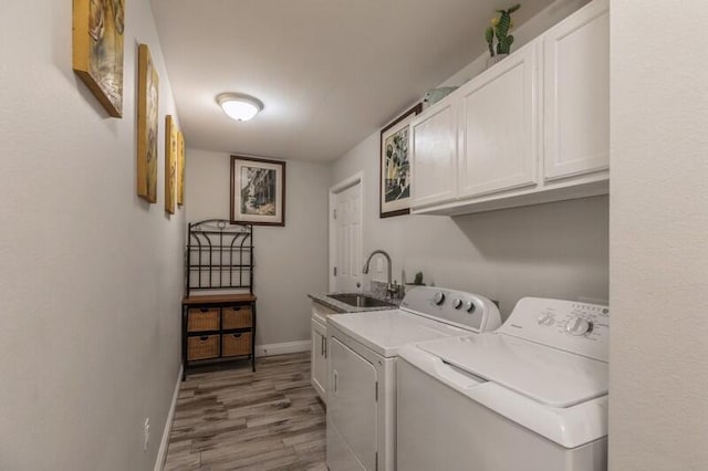 washroom featuring sink, cabinets, washer and clothes dryer, and hardwood / wood-style flooring