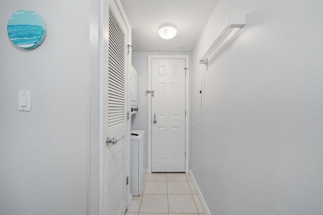 corridor featuring washer / dryer and light tile patterned floors