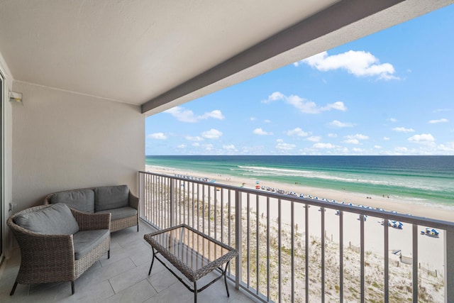 balcony featuring a view of the beach, an outdoor hangout area, and a water view