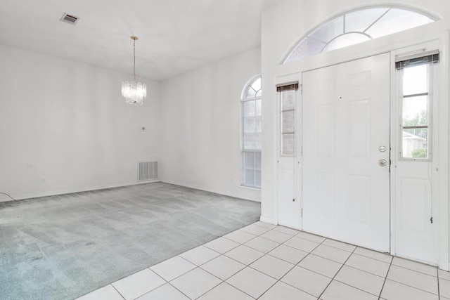 entrance foyer featuring light carpet and a chandelier