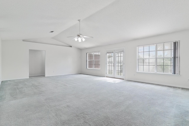 carpeted spare room with ceiling fan, vaulted ceiling, french doors, and a textured ceiling