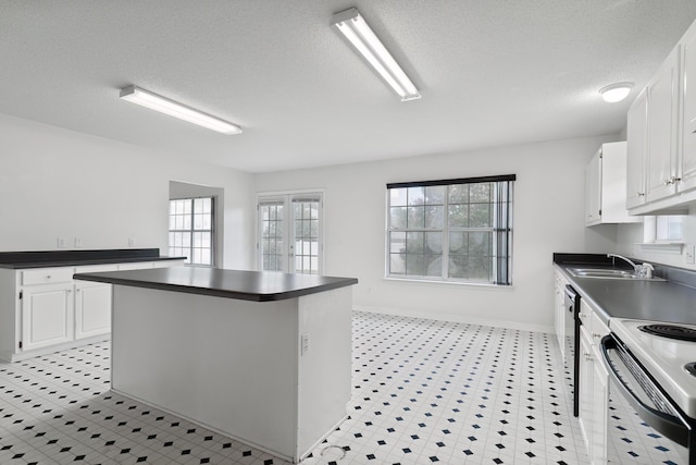 kitchen with a wealth of natural light, white cabinetry, sink, a center island, and french doors