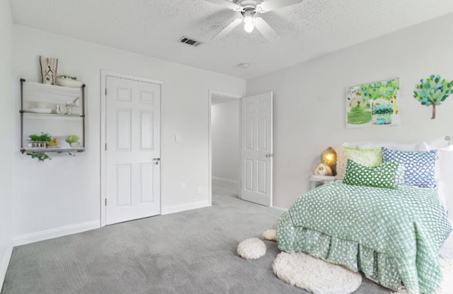 carpeted bedroom with ceiling fan and a textured ceiling