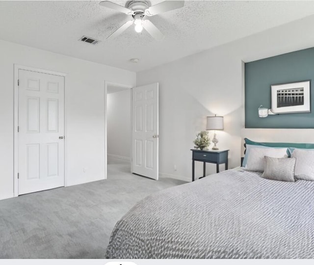 carpeted bedroom with ceiling fan and a textured ceiling