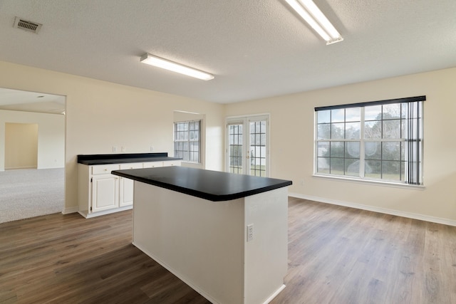 kitchen featuring visible vents, white cabinetry, french doors, dark countertops, and plenty of natural light