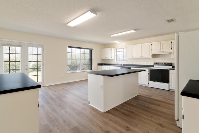 kitchen with visible vents, electric stove, dark countertops, wood finished floors, and under cabinet range hood