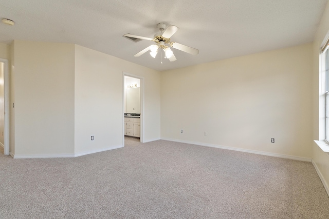 unfurnished room featuring light carpet, plenty of natural light, a ceiling fan, and baseboards