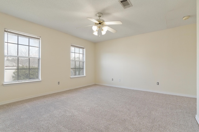 carpeted spare room with a ceiling fan, visible vents, a textured ceiling, and baseboards