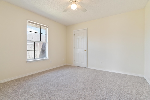 spare room featuring ceiling fan, baseboards, a textured ceiling, and light colored carpet