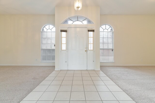 entryway with a healthy amount of sunlight, light carpet, baseboards, and light tile patterned flooring