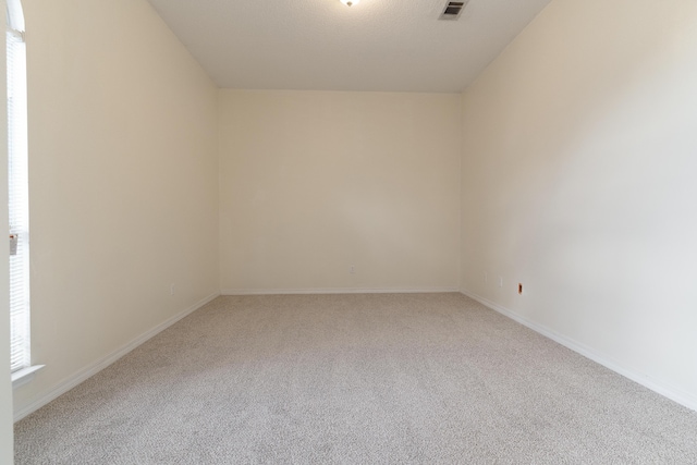 empty room with carpet floors, visible vents, and baseboards