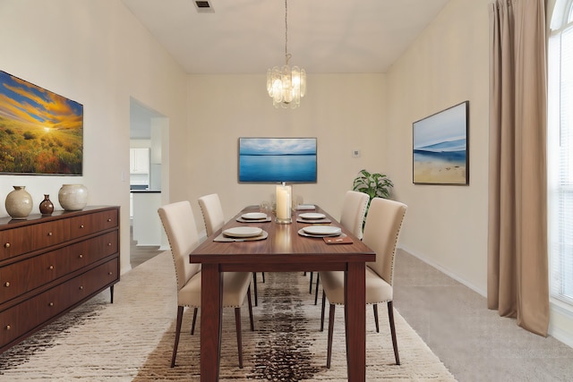 dining space with light carpet, visible vents, baseboards, and a notable chandelier