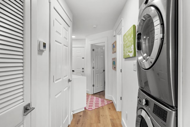 clothes washing area featuring stacked washing maching and dryer and light hardwood / wood-style flooring