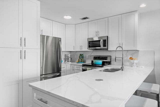 kitchen featuring appliances with stainless steel finishes, a breakfast bar, white cabinets, and sink