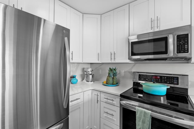 kitchen featuring stainless steel appliances, white cabinetry, and backsplash