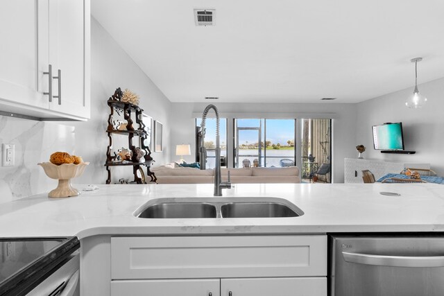 kitchen featuring light stone counters, dishwasher, decorative light fixtures, white cabinets, and sink