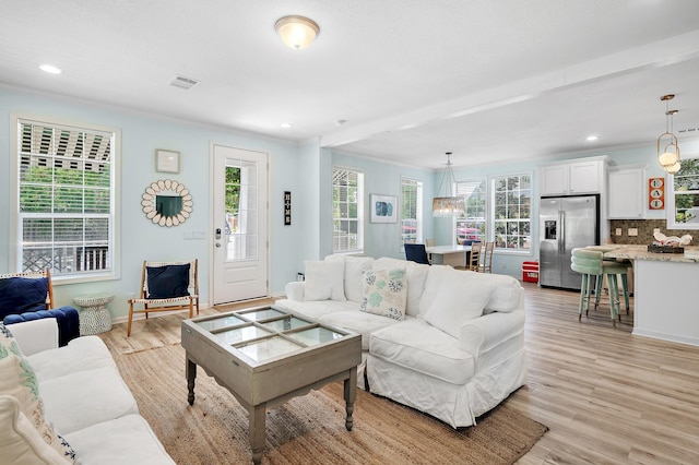 living room with light wood-type flooring and crown molding