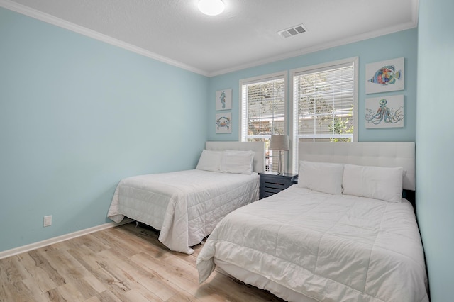 bedroom with ornamental molding, light hardwood / wood-style flooring, and a textured ceiling