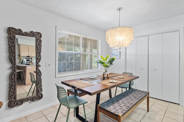 dining space featuring a textured ceiling, light tile patterned floors, baseboards, and a chandelier