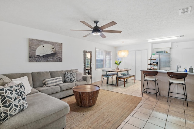 living room with a textured ceiling, ceiling fan, and light tile patterned floors