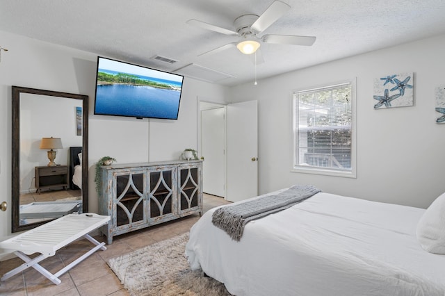 tiled bedroom with a ceiling fan, visible vents, and a textured ceiling