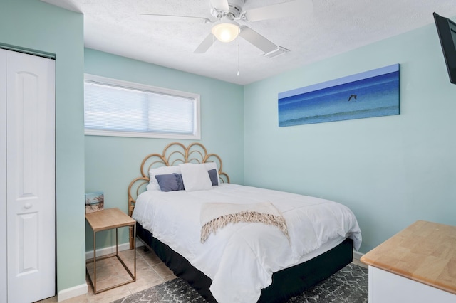 tiled bedroom featuring ceiling fan, baseboards, a closet, and a textured ceiling