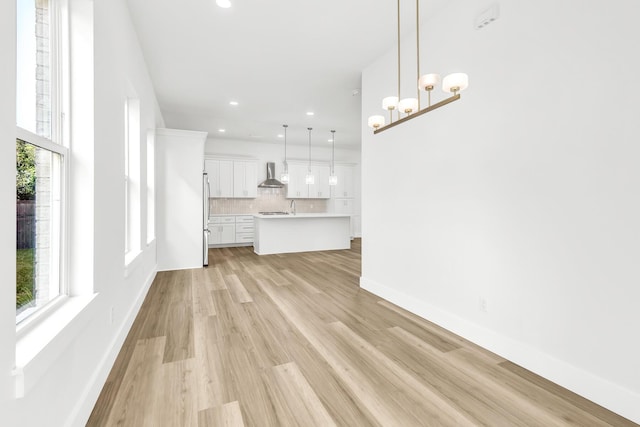 unfurnished living room with sink, light hardwood / wood-style floors, and an inviting chandelier