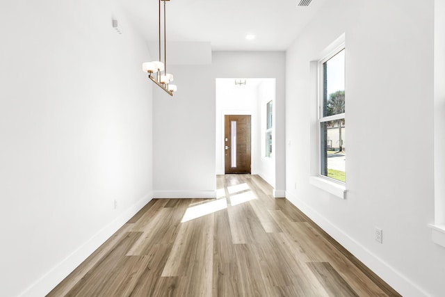 entrance foyer with light hardwood / wood-style floors and an inviting chandelier