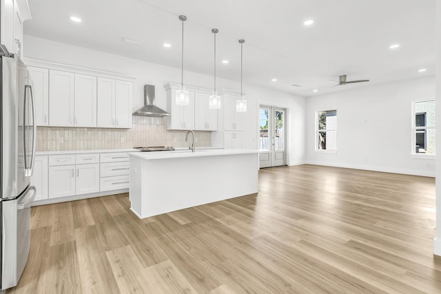 kitchen featuring ceiling fan, white cabinets, wall chimney range hood, and appliances with stainless steel finishes