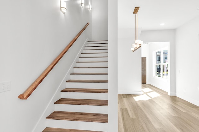 staircase featuring hardwood / wood-style flooring and a notable chandelier