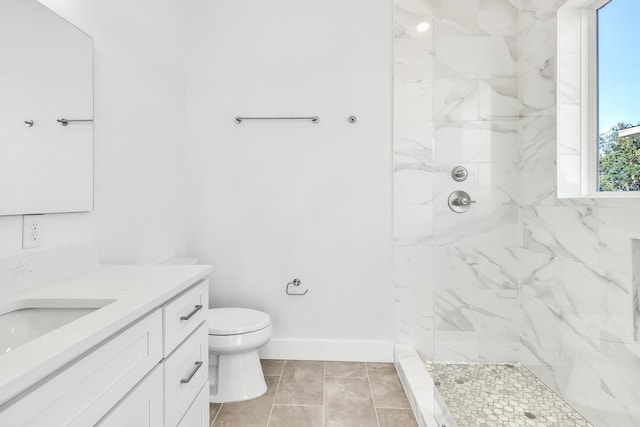 bathroom featuring tiled shower, vanity, tile patterned flooring, and toilet