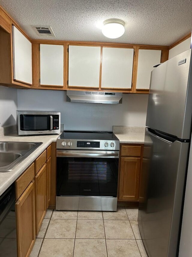 kitchen with sink, appliances with stainless steel finishes, a textured ceiling, and light tile patterned flooring