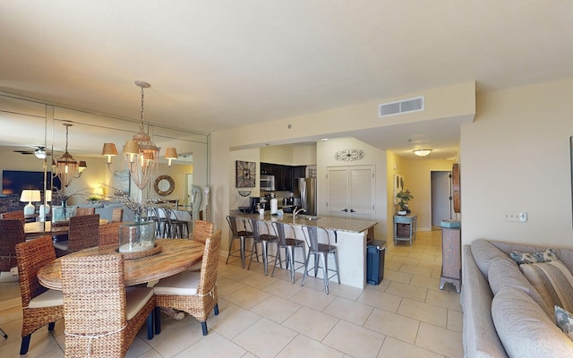 tiled dining room featuring ceiling fan with notable chandelier and sink