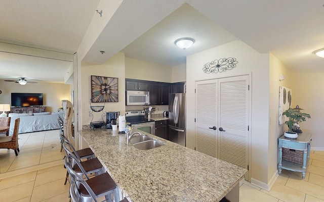 kitchen featuring sink, kitchen peninsula, a kitchen bar, light tile patterned flooring, and appliances with stainless steel finishes