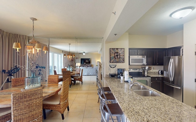 kitchen featuring light stone countertops, appliances with stainless steel finishes, sink, pendant lighting, and light tile patterned flooring