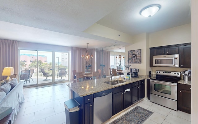 kitchen featuring light stone counters, kitchen peninsula, decorative light fixtures, light tile patterned flooring, and appliances with stainless steel finishes