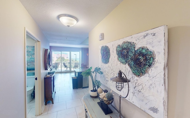 hallway with a textured ceiling and light tile patterned flooring