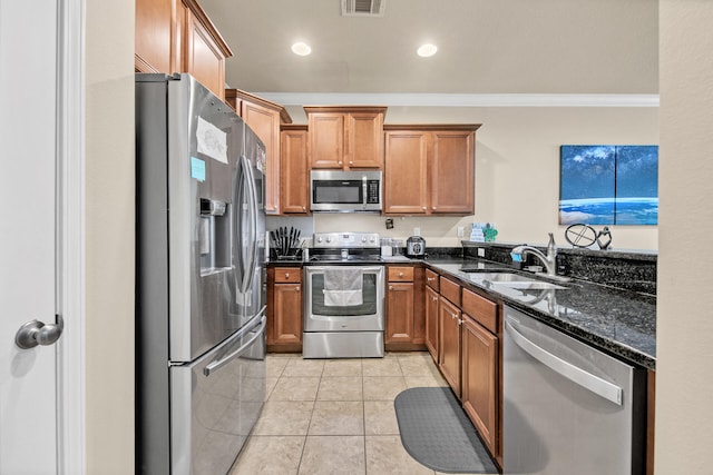 kitchen with sink, crown molding, dark stone countertops, light tile patterned floors, and stainless steel appliances