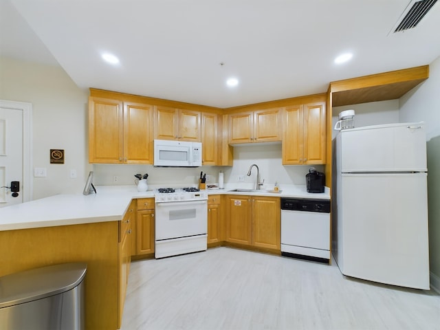 kitchen with kitchen peninsula, sink, white appliances, and light hardwood / wood-style flooring