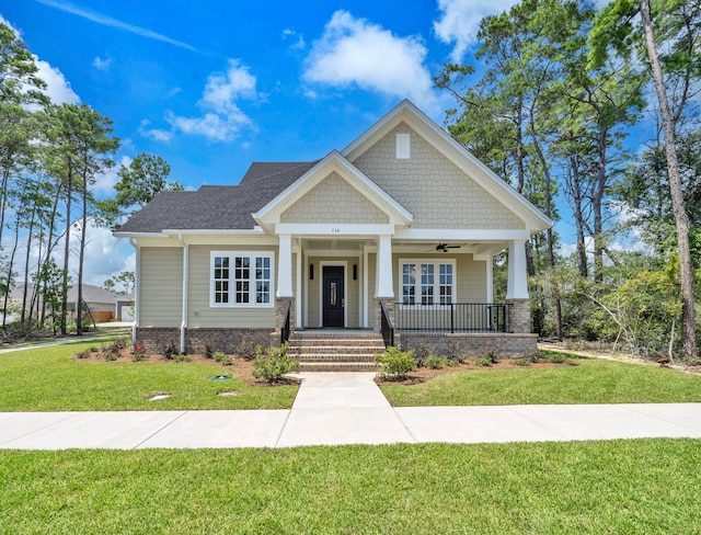 craftsman-style house with a ceiling fan, covered porch, roof with shingles, and a front lawn