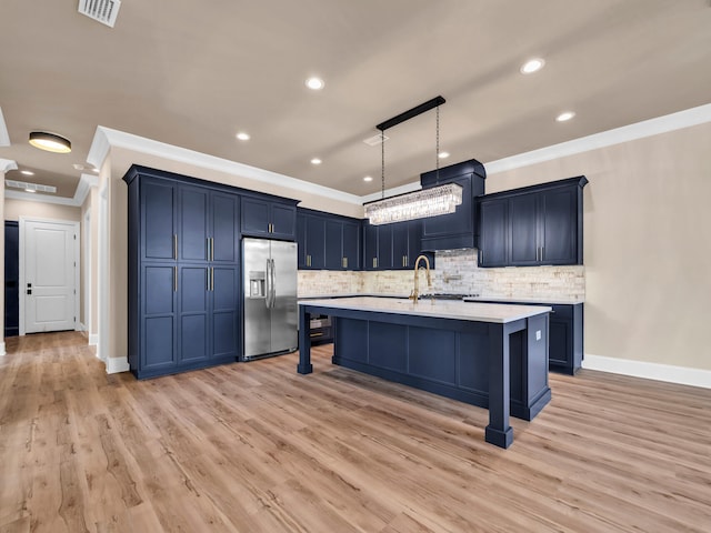 kitchen featuring pendant lighting, decorative backsplash, light wood-type flooring, ornamental molding, and stainless steel fridge