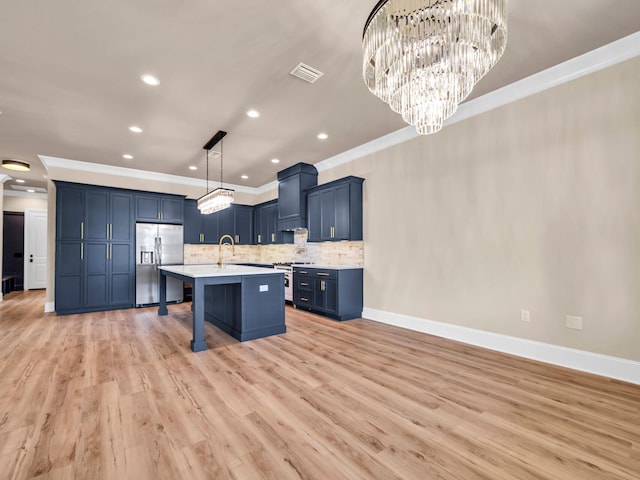 kitchen featuring stainless steel refrigerator with ice dispenser, hanging light fixtures, an island with sink, a kitchen bar, and light hardwood / wood-style floors