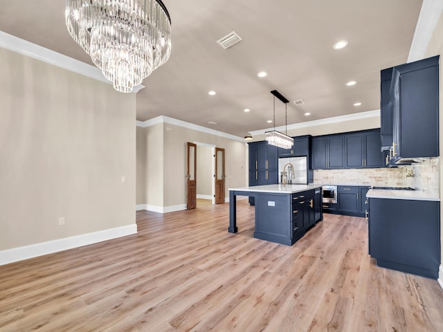 kitchen featuring visible vents, light countertops, tasteful backsplash, a kitchen bar, and a center island with sink