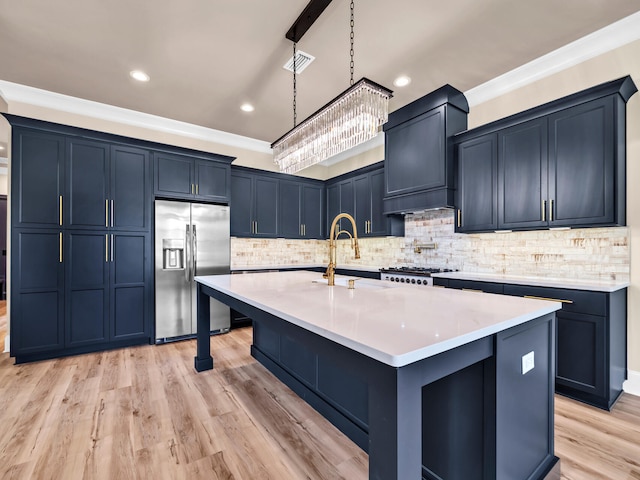 kitchen featuring pendant lighting, stainless steel fridge with ice dispenser, an island with sink, light hardwood / wood-style floors, and backsplash