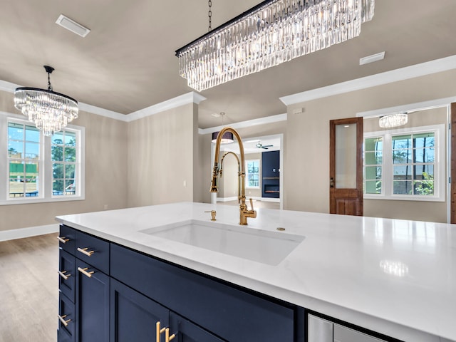 kitchen with pendant lighting, sink, a healthy amount of sunlight, and crown molding