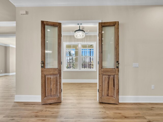 interior space featuring a notable chandelier, light hardwood / wood-style floors, and crown molding