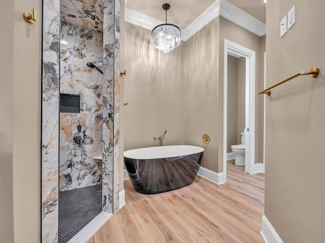 full bath with a marble finish shower, toilet, wood finished floors, a freestanding tub, and baseboards